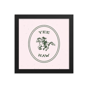 May include: A framed print with a pink background and a green circle containing a cowboy riding a horse. The circle has the text "YEE HAW" in it.