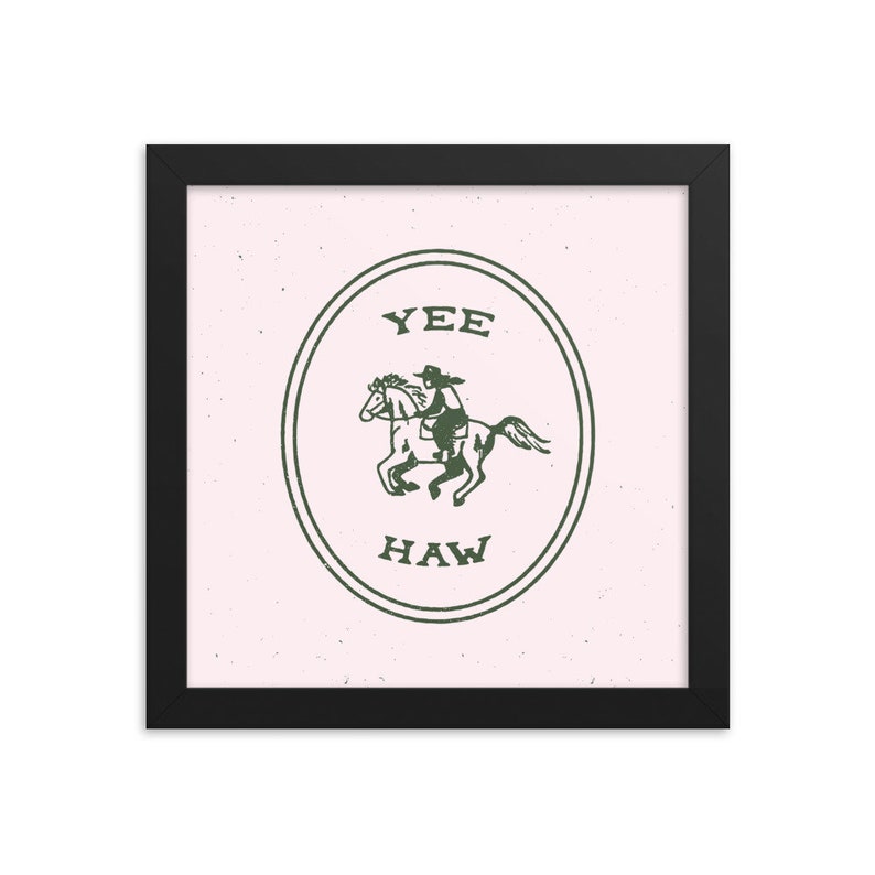 May include: A framed print with a pink background and a green circle containing a cowboy riding a horse. The circle has the text "YEE HAW" in it.