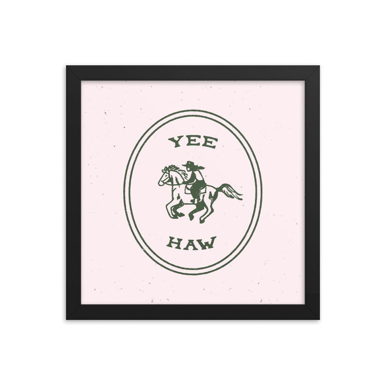 May include: A framed print with a pink background and a green illustration of a cowboy riding a horse inside a circle with the text "YEE HAW" in green.