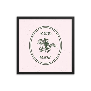 May include: A framed print with a pink background and a green circle containing a cowboy riding a horse. The circle has the words "YEE HAW" written inside.