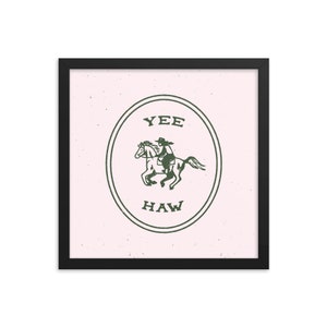 May include: A framed print with a pink background and a green circle containing a cowboy riding a horse. The circle has the text "YEE HAW" inside.