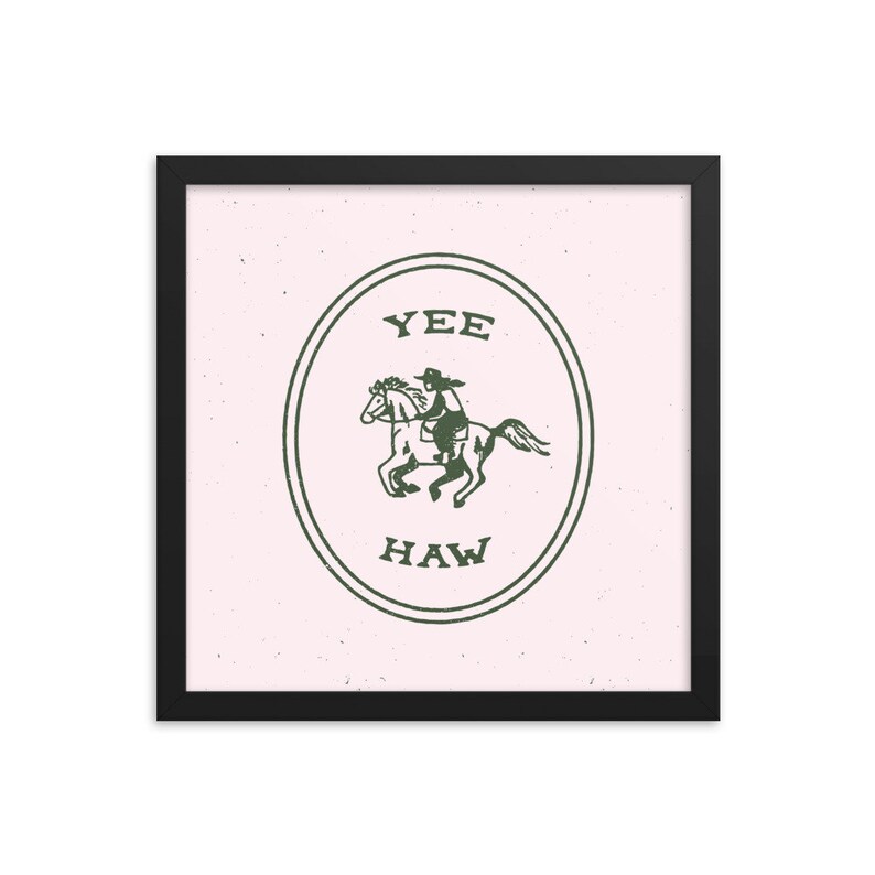May include: A framed print with a pink background and a green circle containing a cowboy riding a horse. The circle has the text "YEE HAW" inside.