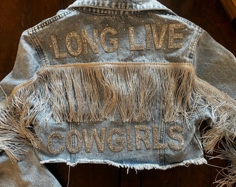 Könnte beinhalten: Eine hellblaue Jeansjacke mit Fransenbesatz und Strasssteinen, die "LONG LIVE COWGIRLS" auf der Rückseite buchstabieren.