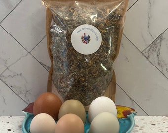 May include: A blue ceramic egg holder shaped like a chicken with six brown, white, and tan eggs inside. A brown paper bag with a clear plastic window contains dried herbs and a white sticker with the text "www.faithandfarms.com" and a picture of a chicken.