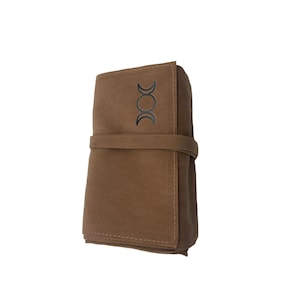 Puede incluir: Una bolsa de gamuza marr&oacute;n con un s&iacute;mbolo de triple luna en la parte delantera. La bolsa est&aacute; doblada y atada con una correa marr&oacute;n.