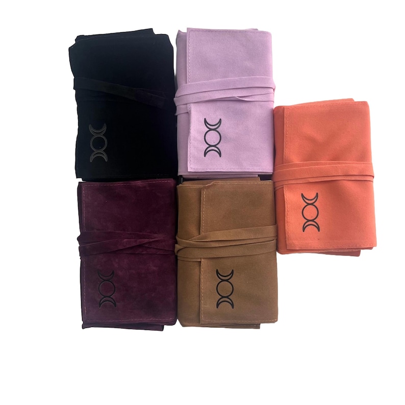 Puede incluir: Cinco bolsas de ante de diferentes colores con un s&iacute;mbolo de triple luna bordado en la parte delantera. Las bolsas son de color negro, morado, marr&oacute;n, naranja y morado claro.