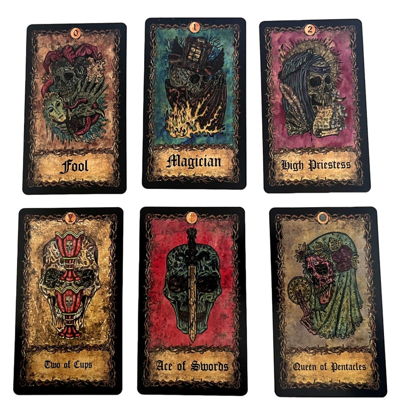 May include: A set of ten tarot cards with black borders and ornate gold frames. The cards feature illustrations of skulls and other imagery. The card names are printed in black at the bottom of each card. The card names are: Fool, Magician, High Priestess, Two of Cups, Ace of Swords, Queen of Pentacles.
