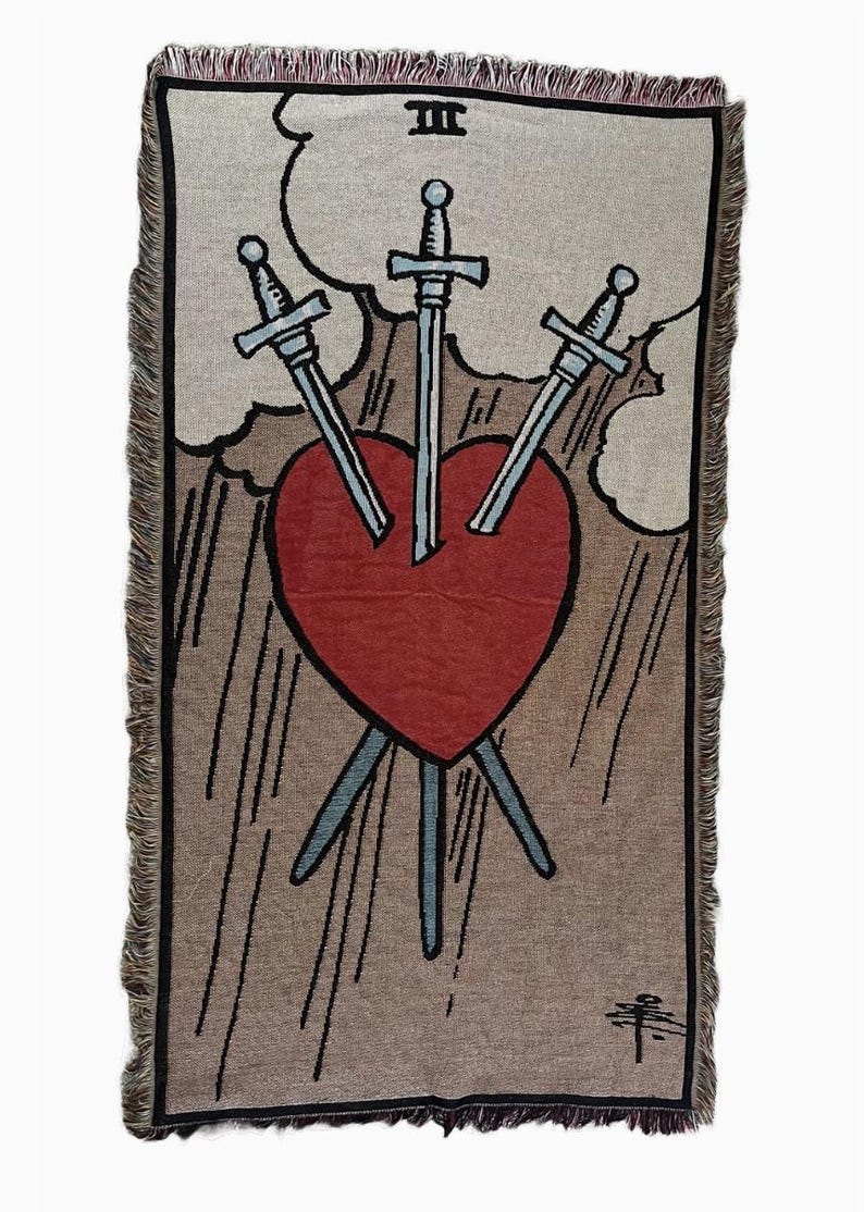 May include: A tapestry depicting the Three of Swords tarot card. The card features a red heart pierced by three swords, symbolizing heartbreak and sorrow. The background is a beige color with clouds and a brown border.