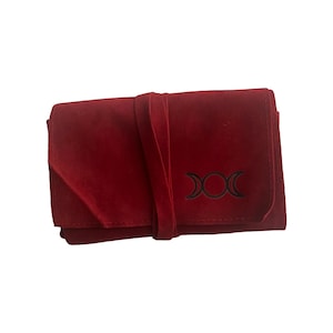 May include: A red velvet pouch with a black triple moon symbol. The pouch has a tie closure.
