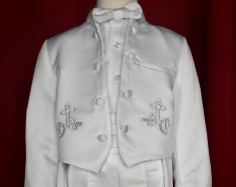 May include: White satin suit jacket with a stand-up collar and silver embroidered crosses on the front.