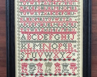 May include: A framed cross-stitch sampler with a white background and green and red embroidery. The sampler features the alphabet, numbers, and the text "JAMES ZIEGLER - 1823."