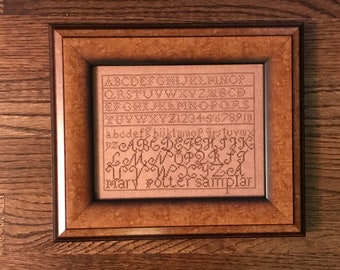 Könnte beinhalten: Ein gerahmter Stich mit dem Alphabet, Zahlen und dem Text "Mary Potter sampler".