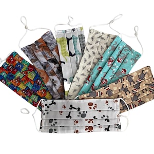 May include: A set of ten colorful fabric face masks with various patterns, including cats, monkeys, paw prints, and bees. The masks are pleated and have white elastic ear loops.