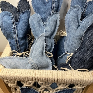 May include: A basket filled with handmade denim bunny rabbit decorations. The bunnies are made from repurposed denim fabric and have a rustic, farmhouse style.
