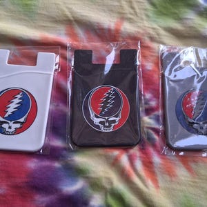 May include: Three phone card holders in white, black, and gray, each featuring a Steal Your Face skull logo in a red circle with a blue lightning bolt. The holders are packaged in clear plastic.