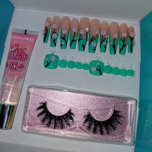 Könnte beinhalten: Ein Beauty-Set mit künstlichen Nägeln, Zehennägeln, falschen Wimpern und Lipgloss. Die Nägel und Zehennägel sind mit einem floralen Design in Rosa und Grün verziert. Die Lipgloss-Tube ist rosa mit dem Text "Broadway". Die falschen Wimpern sind schwarz.