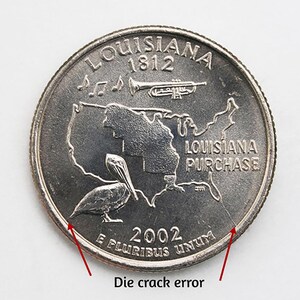May include: A silver 2002 Louisiana quarter coin with a die crack error. The coin features a pelican, musical notes, a trumpet, and the text "Louisiana 1812" and "Louisiana Purchase". The coin also has the text "E PLURIBUS UNUM".