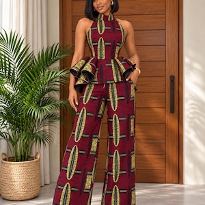 May include: A two-piece outfit consisting of a sleeveless high-neck peplum top and matching wide-leg trousers. The garment features a deep burgundy base color with a repeating geometric pattern in yellow, black, and white throughout the fabric.