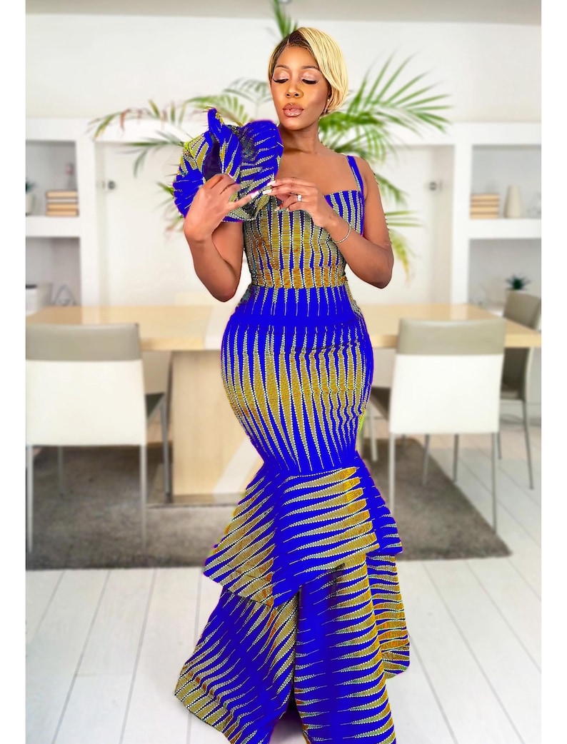 May include: A floor-length sleeveless dress featuring a vibrant blue and mustard yellow geometric pattern. The garment has a fitted bodice with a square neckline and a tiered, ruffled mermaid-style skirt that flares out toward the bottom hem.