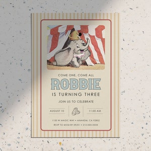 May include: A vintage-style invitation card with a striped background. The card features an illustration of Dumbo the elephant from Disney's Dumbo, peeking out from behind a circus tent. The text on the card reads "Come one, come all Robbie is turning three. Join us to celebrate. August 10, 11:00 AM, 1150 W Magic Way, Anaheim, CA 92802, RSVP to Mom by 09/01, 213-XXX-XXXX".
