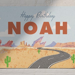 Pode incluir: Um cartão de aniversário com uma paisagem desértica, uma estrada sinuosa e o texto "Happy Birthday NOAH".