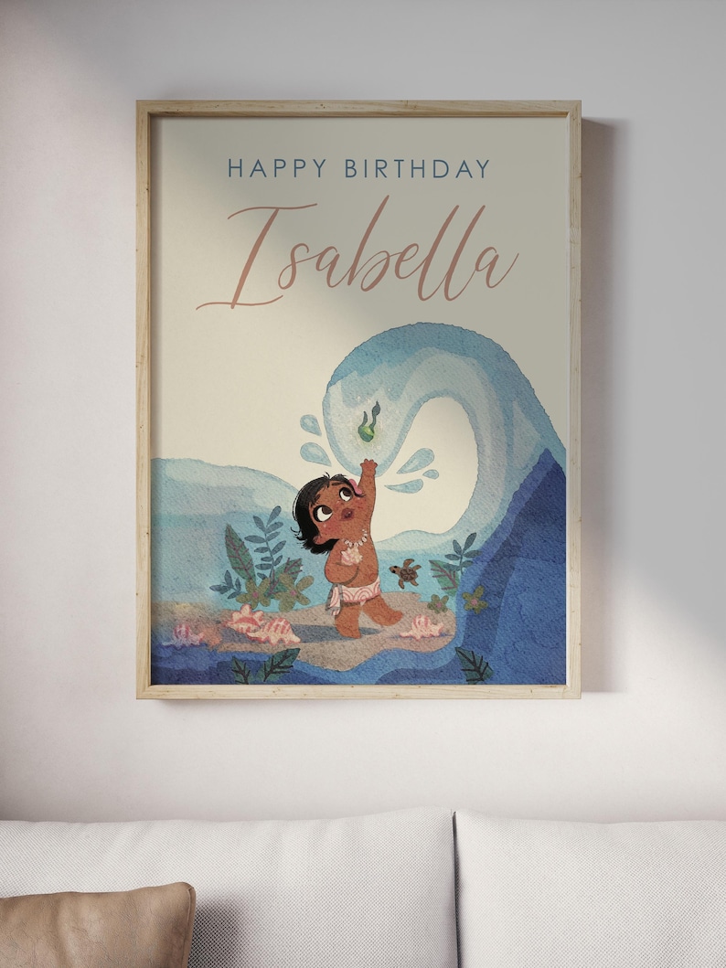 May include: A framed art print with a cartoon illustration of a child on a beach with a large blue wave. The text "Happy Birthday Isabella" is written at the top in a script font. The artwork has a light, airy colour palette.