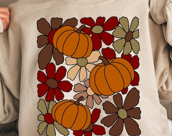 Op de afbeelding: Beige sweatshirt met een herfstthema-ontwerp. Het ontwerp bevat oranje pompoenen en retro bloemen in bruin, rood en beige. De tekst "DIGITAL DOWNLOAD PNG FILE ONLY" staat onderaan.