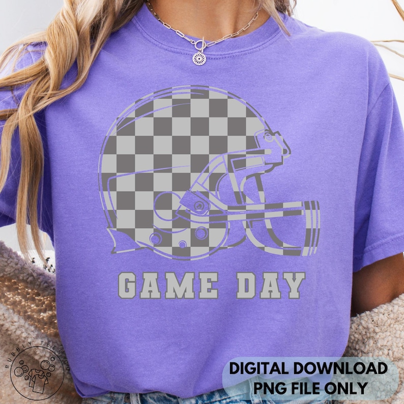 May include: A purple t-shirt featuring a gray and white checkered football helmet design. The words "GAME DAY" are printed in gray below the helmet. The shirt is a digital download, PNG file only.