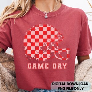 May include: Red t-shirt with a football helmet graphic. The helmet is red and pink checkered, with the words "GAME DAY" printed below. The shirt is a digital download, PNG file only.