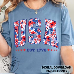 May include: A light blue t-shirt with the word "USA" in a floral pattern of red and blue flowers. Below the word "USA" is the text "EST 1776" with red stars. The shirt is a digital download.