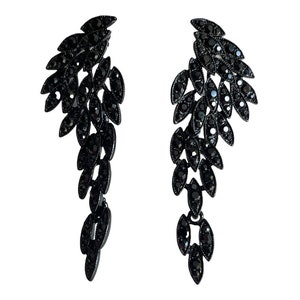 May include: A pair of black dangle earrings with a cascading design of black crystal stones.