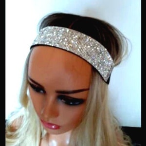 May include: A silver headband with rhinestones. The headband is wide and has a sparkly finish.