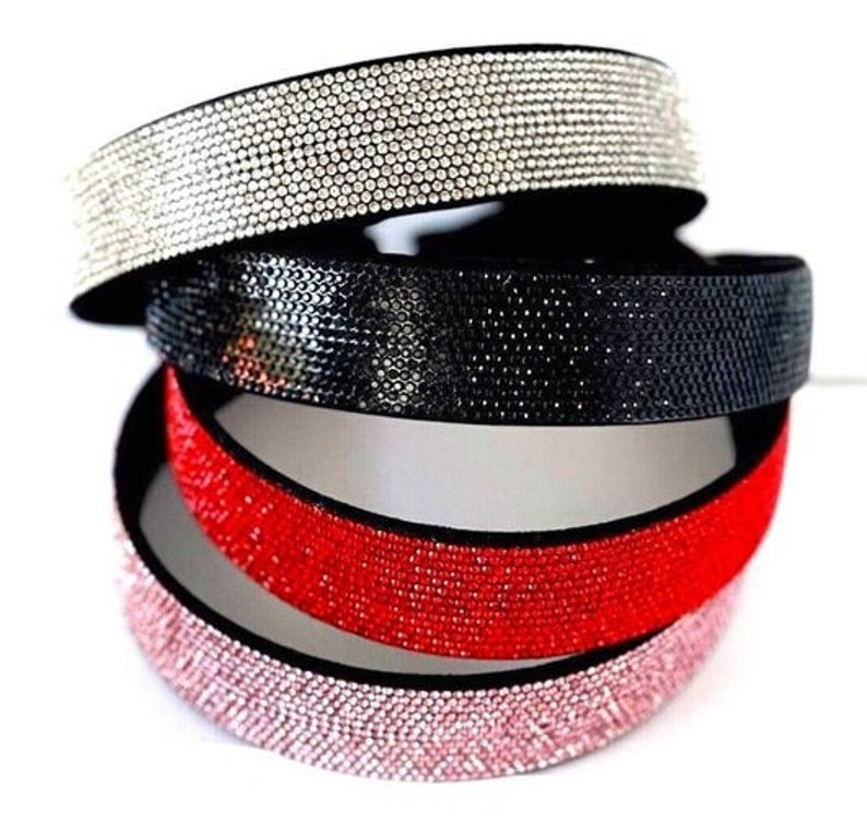 Peut inclure: Quatre bandeaux pour cheveux avec un design scintillant de strass. Les bandeaux sont de couleur noire, rouge, rose et transparente.