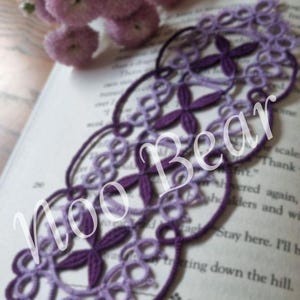May include: A handmade purple tatted lace bookmark with a floral design, resting on a book. The bookmark features the text "Noo Bear" and "Penelope Bookmark". The image also includes a bouquet of purple flowers.