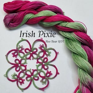 May include: A close-up of a green and pink lace doily with the text "Irish Pixie Noo Bear HDT". The doily is made with a fine thread and has a delicate design.  Two skeins of green and pink embroidery floss are shown in the background.