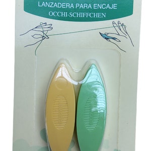 Op de afbeelding: Een verpakking met twee gele en groene plastic tatting shuttles. De verpakking is gelabeld "Clover Tatting Shuttle" en bevat de woorden "Navette &agrave; dentelle", "Lanzadera para encaje" en "Occhi-Schiffchen".