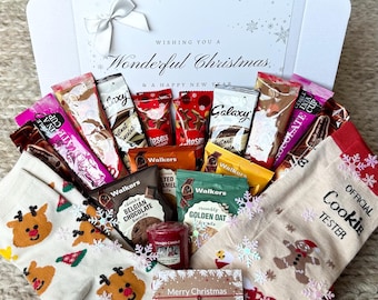 May include: A Christmas gift box overflowing with goodies. Inside are chocolate bars, biscuits, a candle, and two pairs of socks. One pair features reindeer, the other a gingerbread man. The box lid reads "Wishing You a Wonderful Christmas & a Happy New Year."