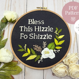 May include: Embroidered hoop art with the phrase "Bless This Hizzle Fo Shizzle" in white text on a black background. The hoop is decorated with green and yellow floral embroidery.
