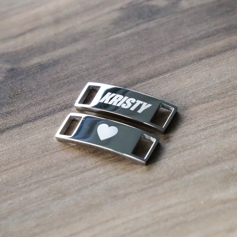 May include: Two silver shoe charms, one with the name "Kristy" engraved and the other with a heart.