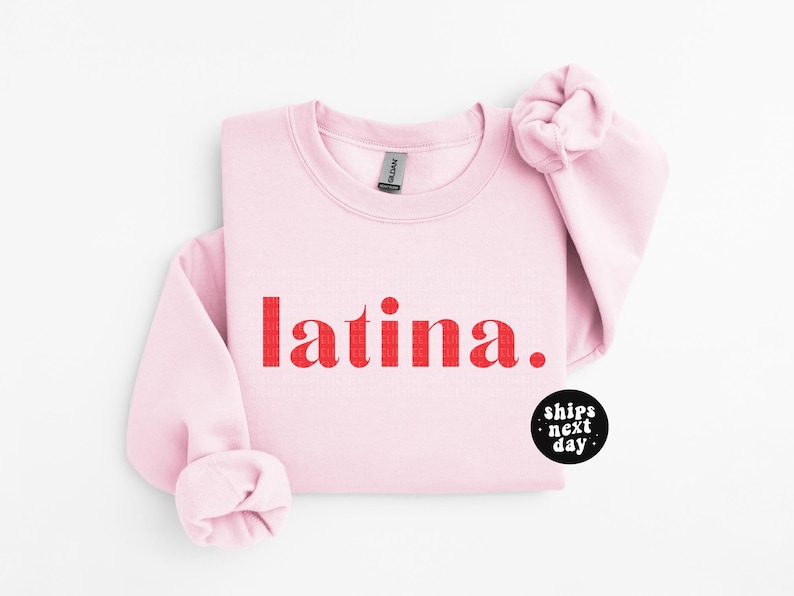 Op de afbeelding: Roze sweatshirt met het woord "latina" in rood op de voorkant.