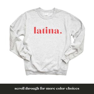 Op de afbeelding: Een grijs sweatshirt met het woord "latina." in rood gedrukt.