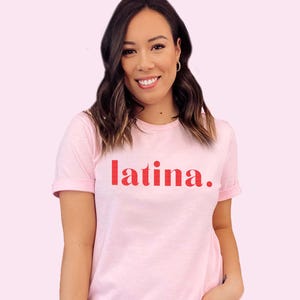 May include: A pink t-shirt with the word "latina" printed in red on the front.