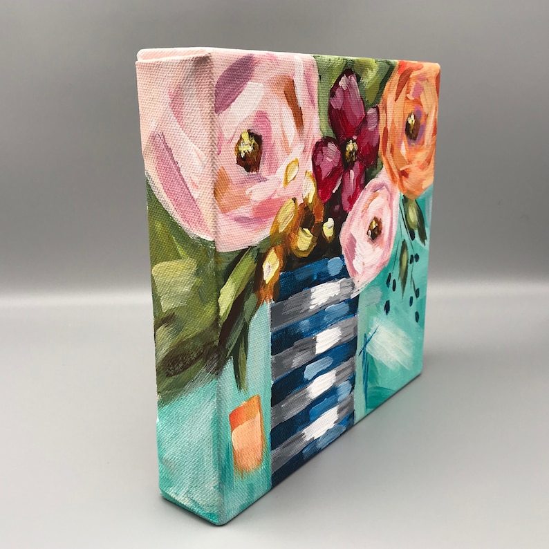 May include: A small canvas painting of a bouquet of pink, orange, and red flowers in a blue and white striped vase. The vase is on a turquoise background.