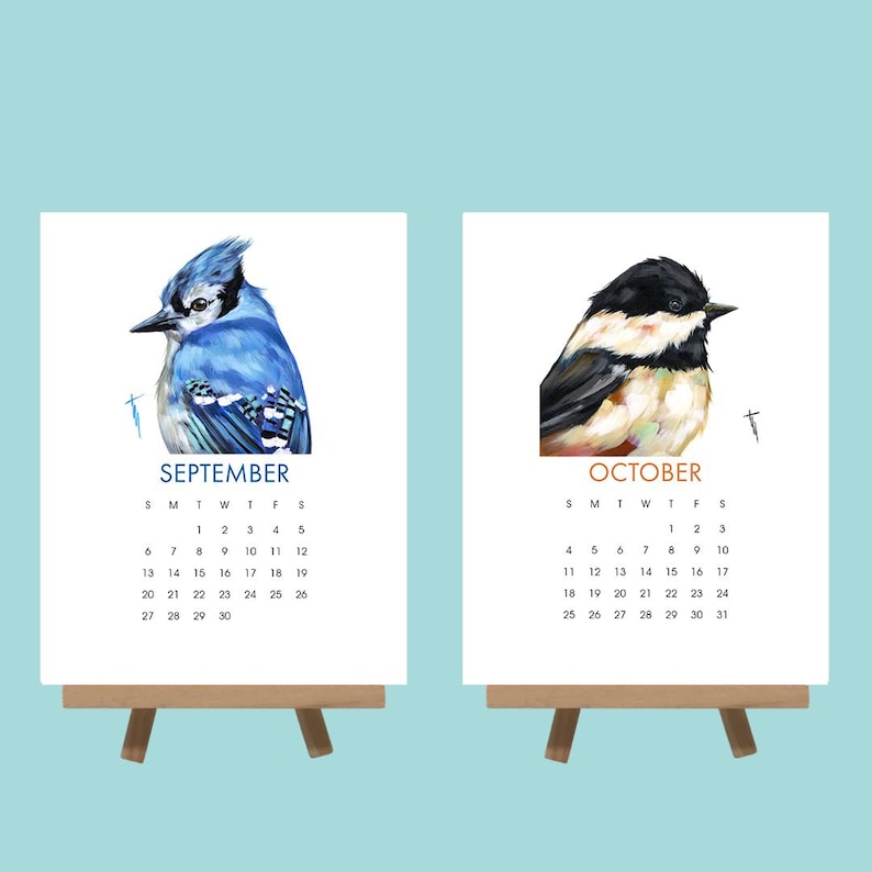 May include: Two small wooden easels each hold a calendar page. One features a blue jay and the word "SEPTEMBER". The other shows a black-capped chickadee and the word "OCTOBER". Each calendar has a month grid.