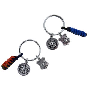 May include: Two silver keychains with a blue and black paracord and an orange and black paracord. Each keychain has a silver charm with a depiction of Saint Michael the Archangel and a silver charm with the word "Police" on it.