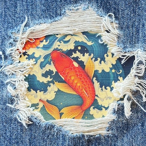 May include: A red and orange koi fish swimming in blue water with white waves. The fish is surrounded by a blue and white pattern. The image is framed by a ripped piece of denim.