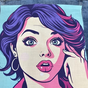 Peut inclure: Un patch de style pop art représentant une femme aux cheveux violets, aux yeux bleus et aux lèvres roses. La femme se touche le visage avec sa main. Le fond est bleu clair et le patch est sur une veste en jean.