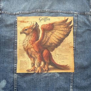 May include: A denim jacket with a large patch showing a griffin illustration. The griffin is in shades of orange, brown, and gold, with the word "Griffin" above it. The patch has a vintage, aged paper appearance, set against a blue denim background.