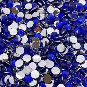 May include: A large pile of blue and silver round rhinestones. The rhinestones are flat-backed and have a shiny finish.
