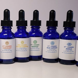 Puede incluir: Siete botellas de vidrio azul cobalto con cuentagotas negros. Cada botella tiene una etiqueta blanca con texto y un símbolo de chakra. Las etiquetas dicen: 1er Chakra Ruby, 2do Chakra Carnelian, 3er Chakra Yellow Sapphire, 4to Chakra Emerald, 5to Chakra Blue Sapphire, 6to Chakra Indigo y 7mo Chakra Amethyst.